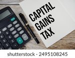 Capital gains tax text message written on note page with calculator top view on wooden background