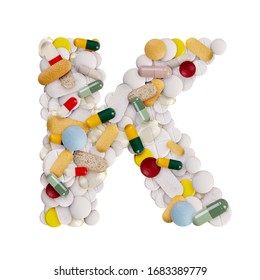 Capital letter K made of various colorful pills, capsules and tablets on isolated white background
