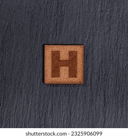 Capital Letter In Square Wooden Tiles    Letter H  On Black Stone Background 