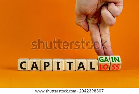 Capital loss or gain symbol. Businessman turns cubes and changes words 'capital loss' to 'capital gain'. Beautiful orange background. Business and capital loss or gain concept. Copy space.