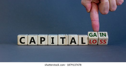 Capital loss or gain symbol. Male hand turns cubes and changes words 'capital loss' to 'capital gain'. Beautiful grey background. Business and capital loss or gain concept. Copy space. - Shutterstock ID 1879137478