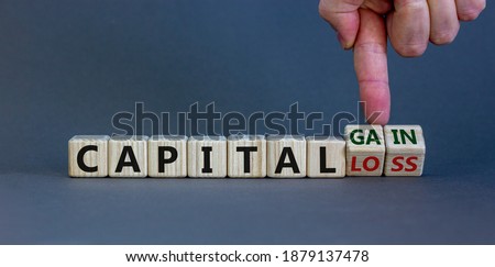 Capital loss or gain symbol. Male hand turns cubes and changes words 'capital loss' to 'capital gain'. Beautiful grey background. Business and capital loss or gain concept. Copy space.