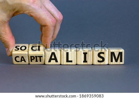 Capitalism or socialism. Hand turns cubes and changes word 'capitalism' to 'socialism'. Beautiful white background, copy space. Business and capitalism or socialism concept.