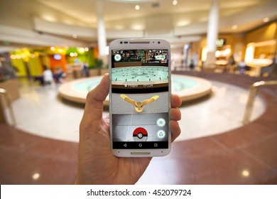 CAPITOLA, CALIFORNIA - JULY 13, 2016: The hit augmented reality smartphone app "Pokemon GO" shows a Pokemon encounter at a mall fountain in the real world. 