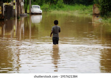 Capivari, SP, Brazil - January 19, 2015: A Young Boy Looks On As He Walks Through A Flooded Street After Heavy Rains Hit A Residential Neighborhood.