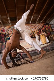 Capoeira Man Performing A Cartwheel Flip Indoors