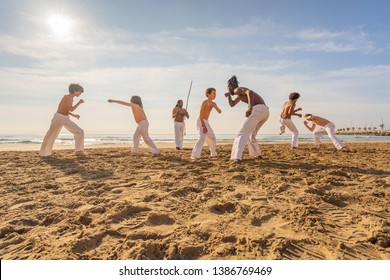 Capoeira team training on the beach - Martial arts athletes performing stunts