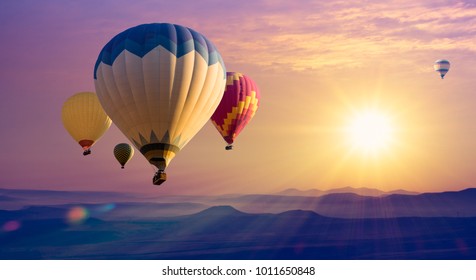 Cappadocia at sunrise - landscape with hot air balloons flying over mountain valley in sunlight and mist. Adventures on Turkey - travel concept background, romantic holiday or ballooning festival.