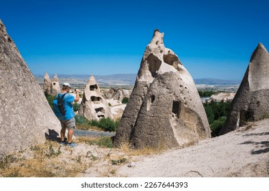 Cappadocia, Tourist takes photo abandoned cave houses inside unusual conical rock formations in the Goreme National Park, Popular travel destination in Turkey - Powered by Shutterstock