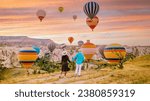 Cappadocia Turkey during sunrise, a mature couple of men and woman on vacation in the hills of Goreme Cappadocia Turkey, men and woman looking sunrise with hot air balloons in Kapadokya Turkey