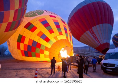 Cappadocia, Turkey / January 12, 2020: Hot air balloons starting to take off over spectacular Cappadocia. Beautiful view of colorful hot air balloons floating in sunrise light. 