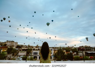 Cappadocia Turkey, September 21, 2022. Back View Girl Watching Hot Air Baloons In The Sky From Rooftop Hotel At Cappadocia