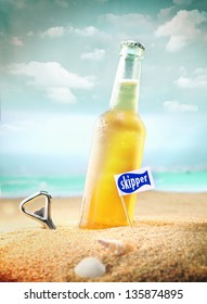 Capped Bottle Of Chilled Fruity Orange Soda Or Ale (beer) Standing In The Golden Sand On A Tropical Beach With A Bottle Opener And Skipper Sign. Look At My Portfolio For More Cocktails.