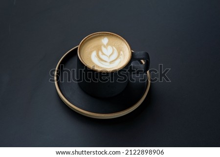 Cappuccino in a black mug on a black background Morning delicious takeaway coffee. Top view of the foam . Creamy foam, fragrant coffee close-up. Fresh coffee