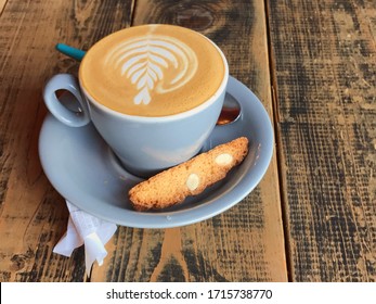 
Cappuccino in a blue cup with biscotti on a wooden table