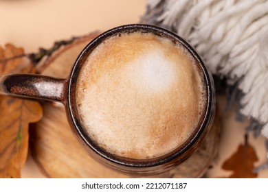 Cappuccino Coffee In A Ceramic Cup, Top View. Milk Foam, Texture. Cappuccino On An Autumn Background With Foliage On A Beige Background With Copy Space.