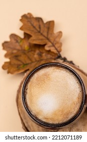 Cappuccino Coffee In A Ceramic Cup, Top View. Milk Foam, Texture. Cappuccino On An Autumn Background With Foliage On A Beige Background With Copy Space.