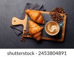 Cappuccino coffee and fresh croissants on stone table. Flat lay