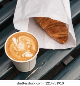 Cappuccino Coffee Latte Art In A Paper Cup , And Croissant, On Wooden Bench, Outdoor.