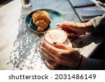 Cappuccino and croissant on the table in the cafe. The morning sunlight falls on the table, beautiful shadows appear. Delicious breakfast.Women