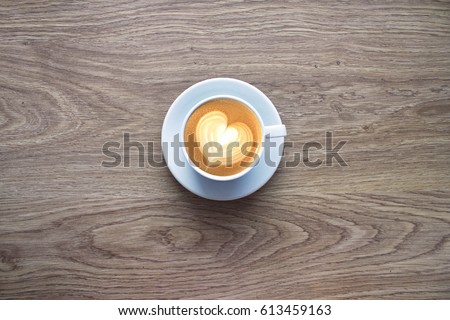 Cappuccino with foam in the form of heart on the crumpled paper background, top view with free copy space for text.
