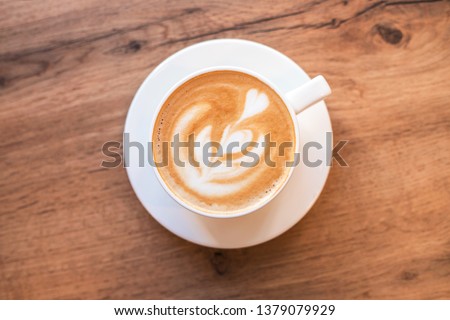 Cappuccino with frothy foam, blue coffee cup top view closeup on white wood background. Flat lay style.