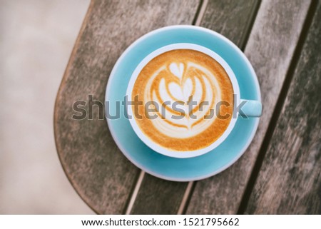 Cappuccino with frothy foam, blue coffee cup top view closeup on gray wooden background. Flat lay style.