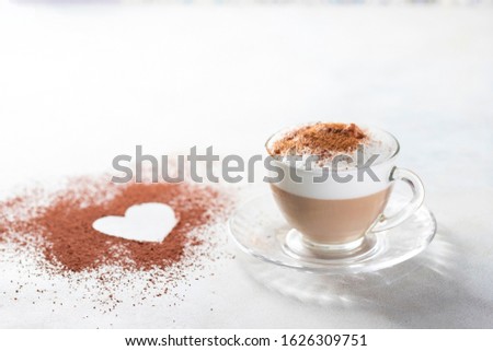 Cappuccino and heart made of cocoa powder on white background. The idea for a festive breakfast, Valentine's Day. Selective focus, copy spacy