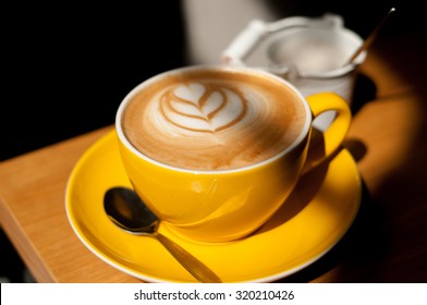 cappuccino with heart in yellow cup on wood table background overhead view cool shadows natural light - Powered by Shutterstock