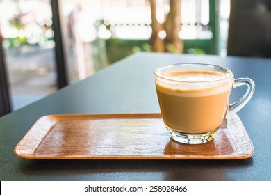 Cappuccino Or Latte Coffee In A Clear Glass Mug On Wooden Tray.