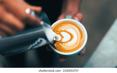Cappuccino or latte with frothy foam, blue coffee cup top view closeup on barista hand background.Cafe and bar, barista making latte art.fresh cappuccino coffee mug in cafe.caffeine roasted arabica. - Shutterstock ID 2150553757