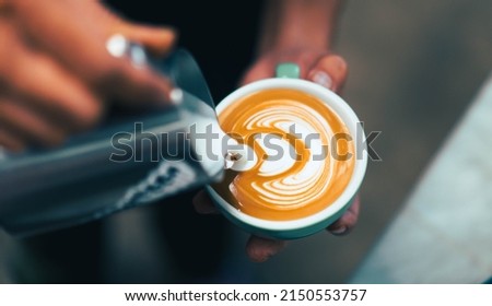 Cappuccino or latte with frothy foam, blue coffee cup top view closeup on barista hand background.Cafe and bar, barista making latte art.fresh cappuccino coffee mug in cafe.caffeine roasted arabica.
