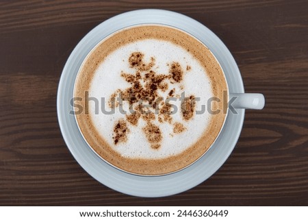 Cappuccino or latte with frothy foam, blue coffee cup top view closeup isolated on white background. Cafe and bar, barista art concept.