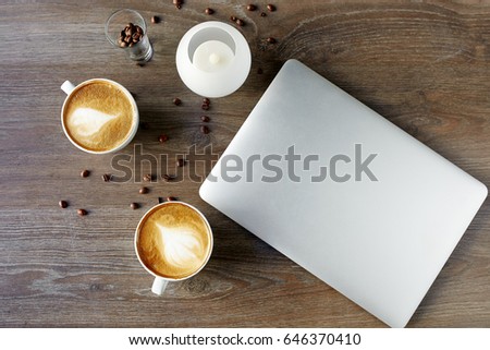 Cappuccino on a table with a laptop on a wooden background with grains of confe