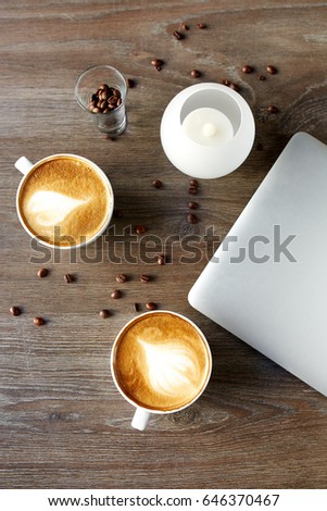 Cappuccino on a table with a laptop on a wooden background with grains of confe