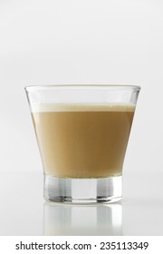 Cappuccino in a transparent cup over white table