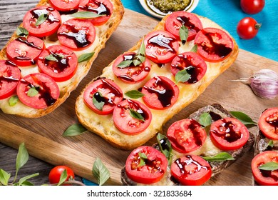 Caprese Garlic Bread Ciabatta On The Cutting Board With Cherry Tomatoes, Mozzarella, Sauce Pesto, And Basil, Italian Style, View From Above 