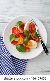 Caprese Salad On White Plate Top View, Wooden Background