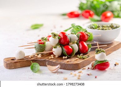 Caprese salad-mozzarella, basil, cherry tomatoes, pesto sauce, skewers. Italian homemade food and a healthy diet concept. - Powered by Shutterstock