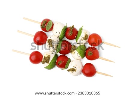 Caprese skewers with tomatoes, mozzarella balls, basil and pesto sauce on white background, top view