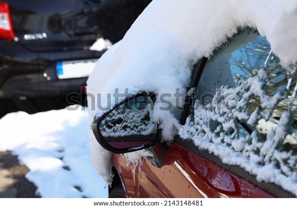 Caps of white snow on\
parked cars.