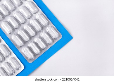 Capsule Pills In Blister Pack On White And Blue Background. Medical And Pharmaceutical Backdrop. Mockup With Copy Space