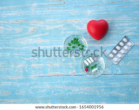 Capsules or druga or pill and rubber hearts are on the wooden table.