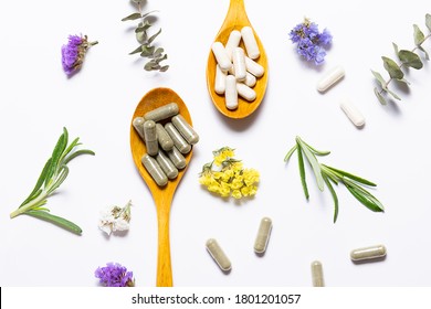 Capsules of natural collagen and herbal detox capsules for beauty and immunity support on white background with flowers and herbs top view. Healthy lifestyle concept.