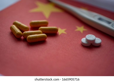 Capsules, Pills And Thermometer On Flag Of China Background. Coronavirus Treatment Concept. 