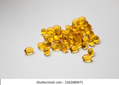 A lot of capsules vitamin D close-up on white background. Bright oil yellow pills isolated. 