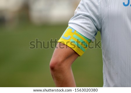 Captain of the football team on the stadium field. Sports background-the hand of the team captain with the identifying distinctive ribbon of the captain, official leader of team of footballers