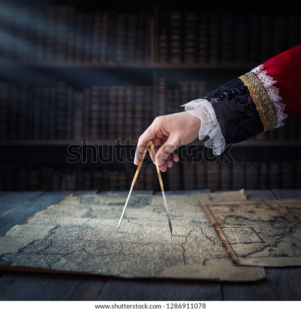 The
captain of the old ship paves the course with the help of vintage
maps and nautical divider. Old discovery, explorer, history,
pirates, travel, geography and navigate
background.