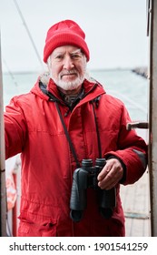 Captain On The Sea Ship. Portrait View Of The Sailor Cruise Team Boat Officer With Binoculars At His Neck Standing At The Yacht Or Boat And Smiling To The Camera. Stock Photo