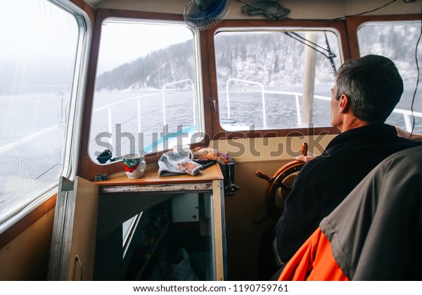 \
Captain of the ship at the wheel, in the cockpit\
of the old boat